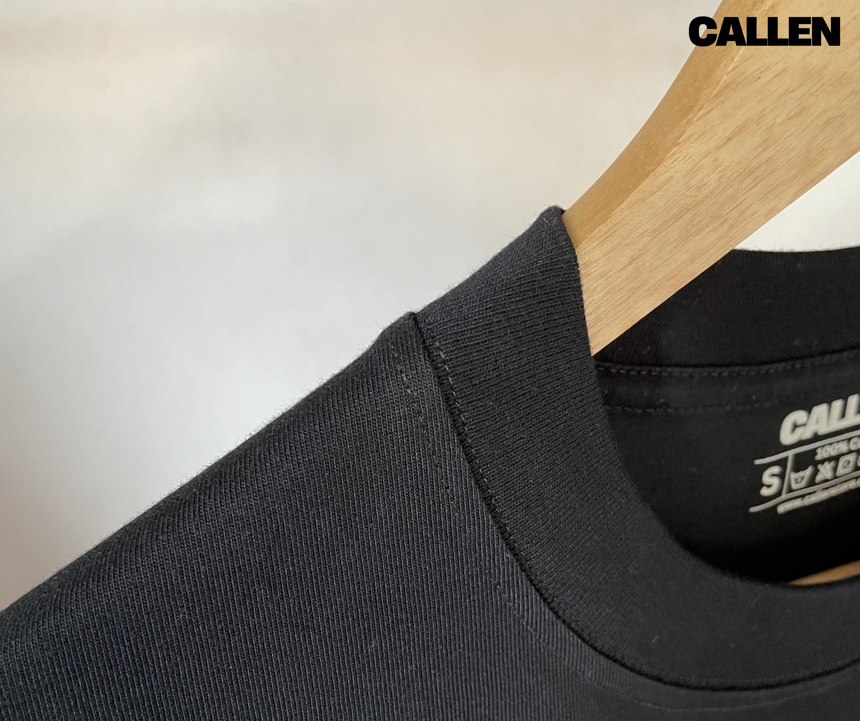 Black 100% cotton t-shirt with 'Callen' branding on a wooden hanger against a neutral background